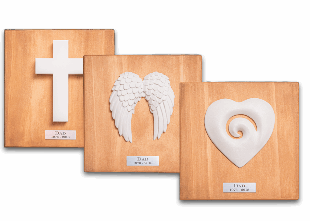 Memorial ornaments — cross, angel wings, and koru heart on wooden boards